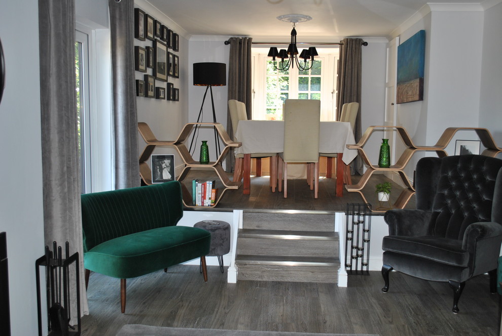 Пример оригинального дизайна: двухуровневая гостиная комната среднего размера в современном стиле с серыми стенами, полом из ламината, печью-буржуйкой, фасадом камина из камня и отдельно стоящим телевизором