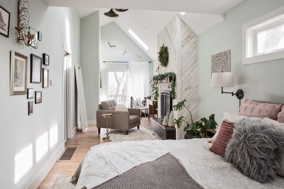 Geräumiges Klassisches Schlafzimmer mit grüner Wandfarbe, hellem Holzboden, Kamin, Kaminumrandung aus Holz, braunem Boden und gewölbter Decke in Denver