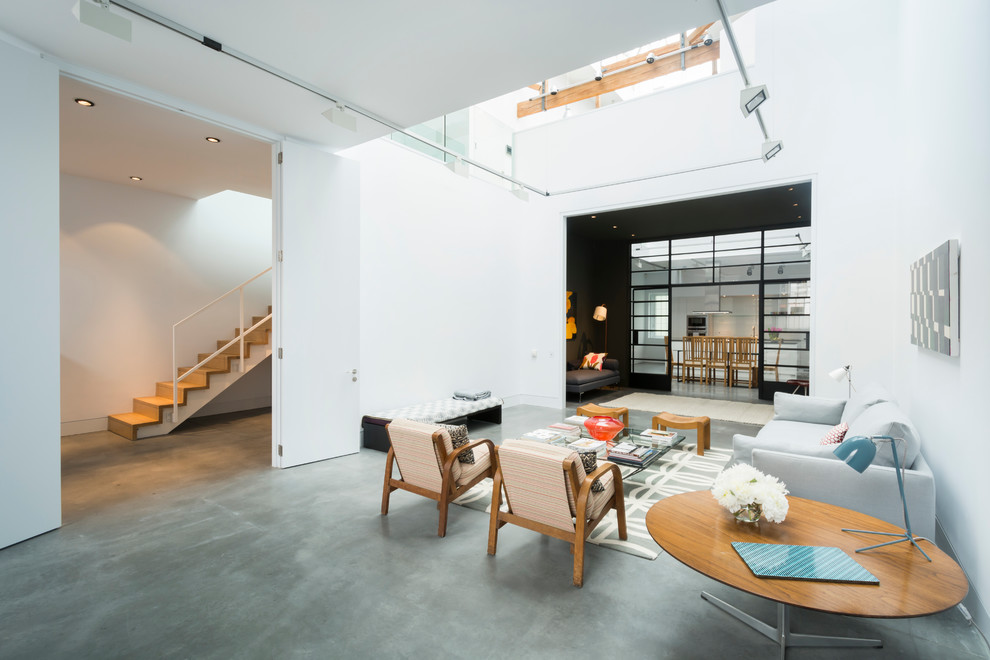 Immagine di un ampio soggiorno industriale con sala formale, pareti bianche e pavimento in cemento