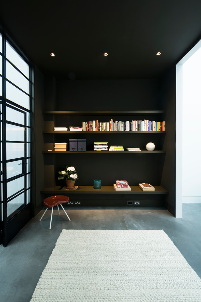 This is an example of an expansive industrial formal open plan living room in London with black walls and concrete flooring.