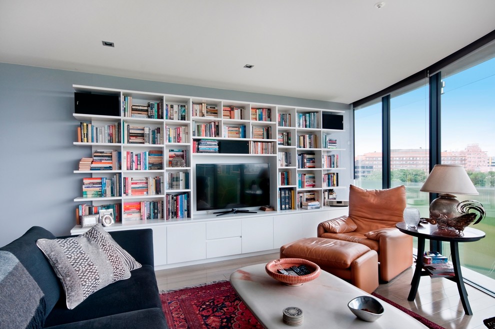 Imagen de salón abierto minimalista grande sin chimenea con paredes azules, suelo de madera en tonos medios y pared multimedia