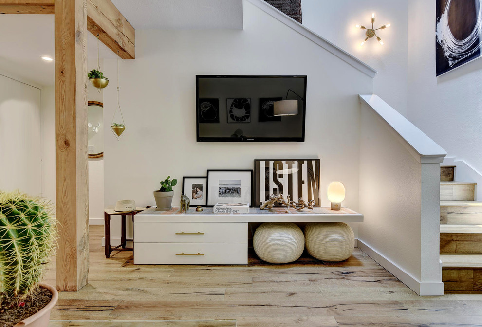 Imagen de salón tipo loft minimalista de tamaño medio sin chimenea con paredes blancas, suelo de madera clara y televisor colgado en la pared