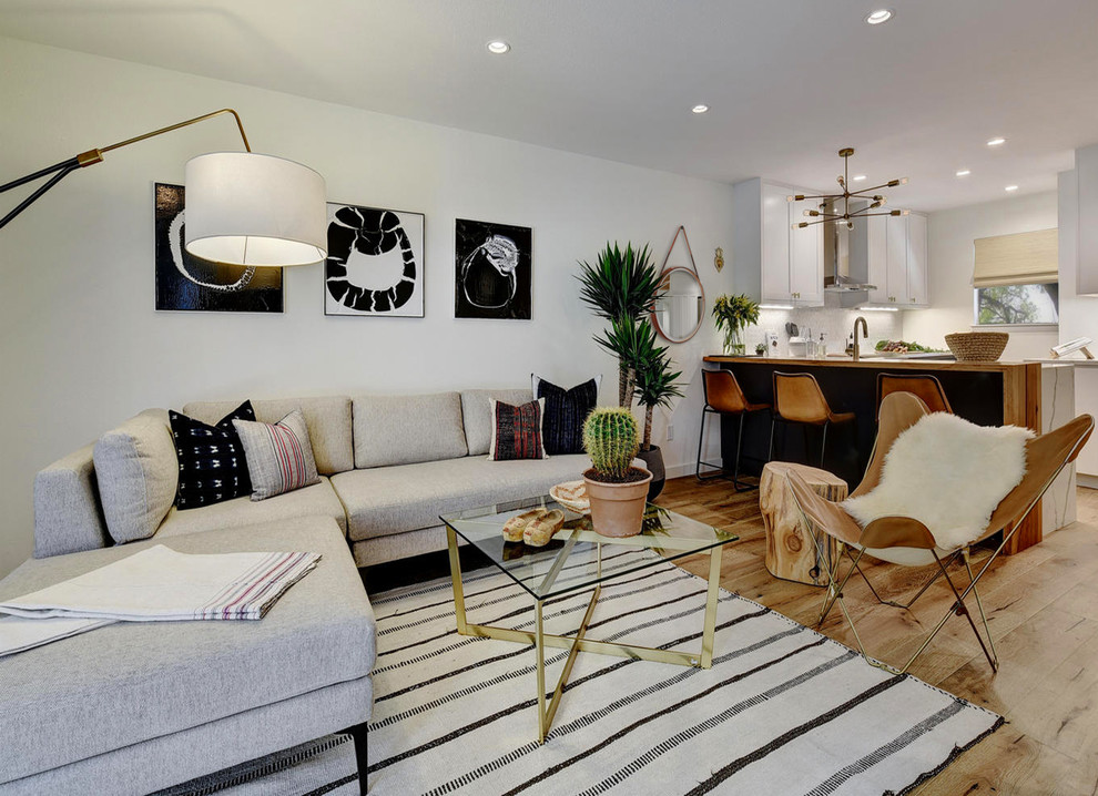 Foto de salón abierto minimalista de tamaño medio sin chimenea con paredes blancas, suelo de madera clara, televisor colgado en la pared y suelo beige