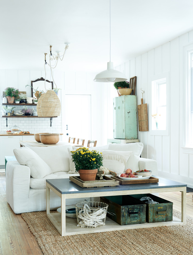 Offenes Country Wohnzimmer mit weißer Wandfarbe, braunem Holzboden und braunem Boden in Sonstige