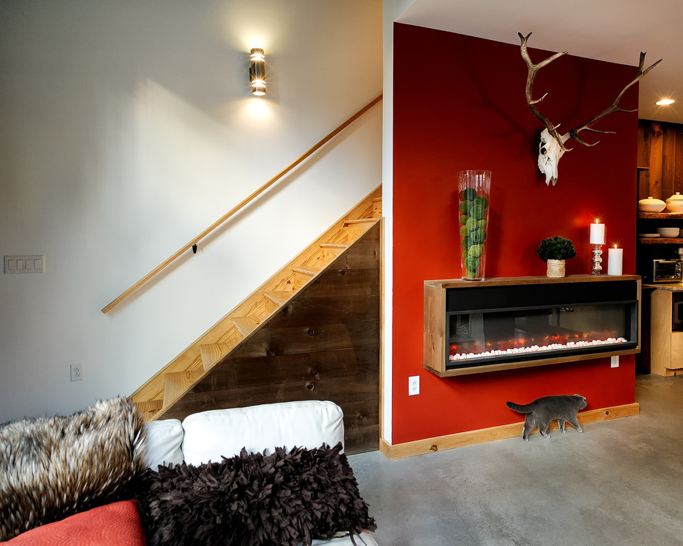 Источник вдохновения для домашнего уюта: большая парадная, двухуровневая гостиная комната в стиле рустика с красными стенами, бетонным полом, подвесным камином, серым полом и фасадом камина из дерева без телевизора