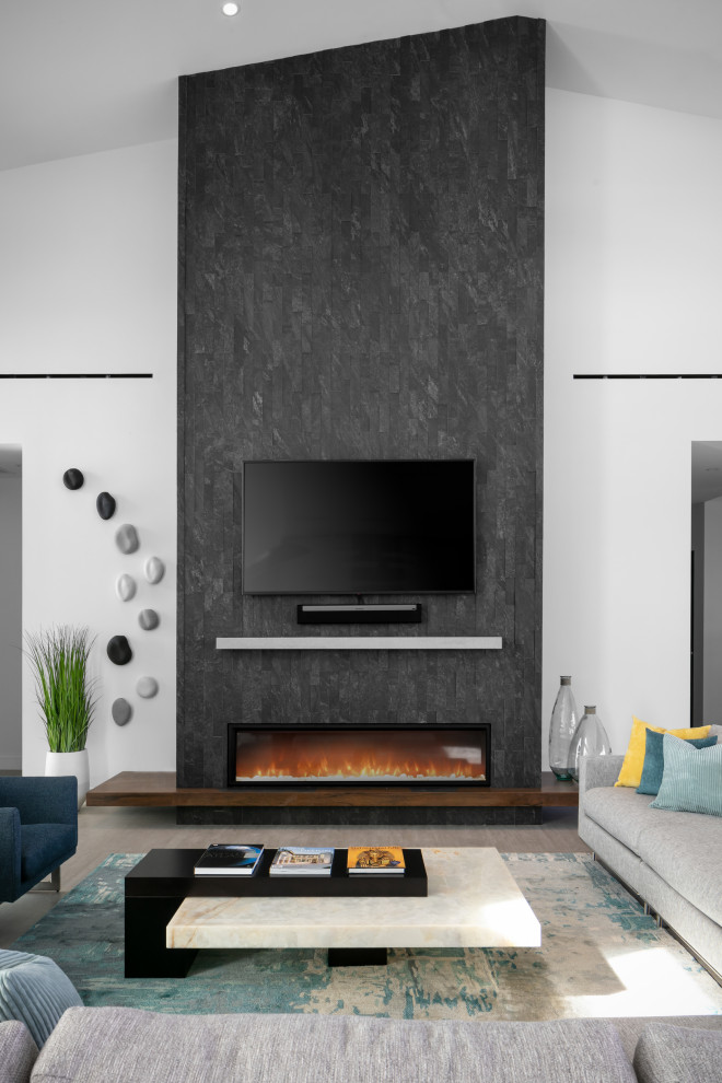 タンパにあるラグジュアリーな巨大なコンテンポラリースタイルのおしゃれなLDK (白い壁、磁器タイルの床、横長型暖炉、積石の暖炉まわり、壁掛け型テレビ、グレーの床、三角天井) の写真