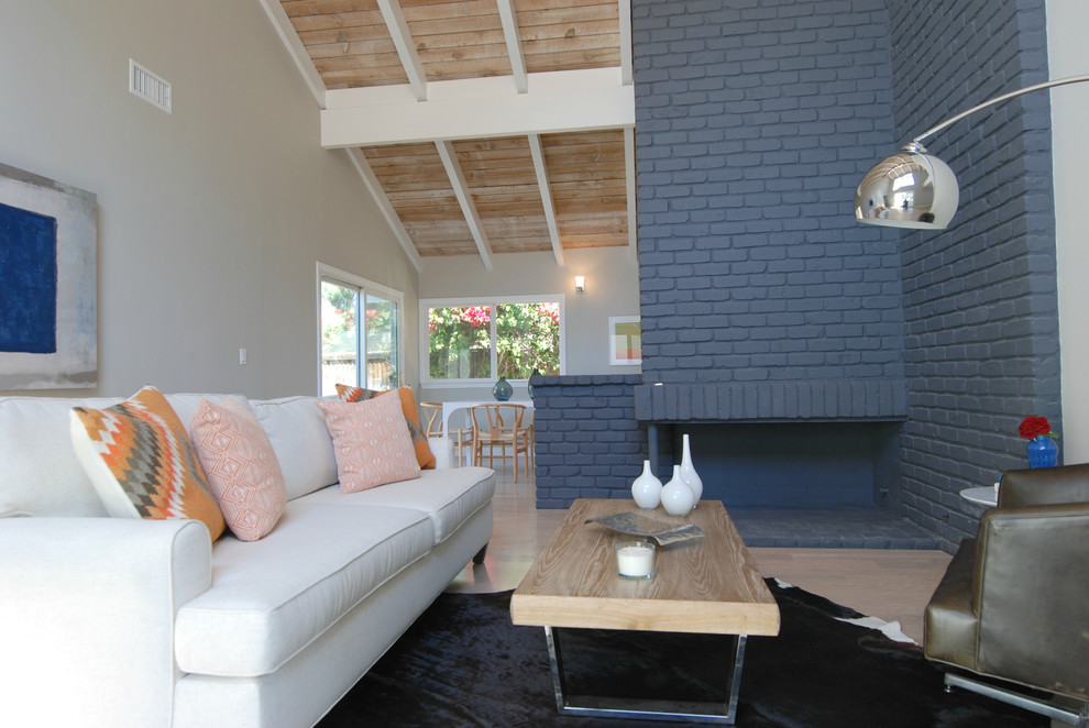 Foto de salón abierto minimalista de tamaño medio sin televisor con suelo de madera clara, chimenea de esquina, marco de chimenea de ladrillo y paredes blancas