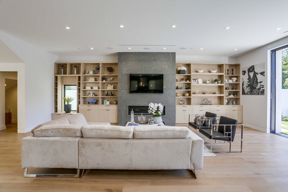 Imagen de salón abierto actual grande con paredes blancas, suelo de madera clara, chimenea lineal, televisor colgado en la pared y suelo beige