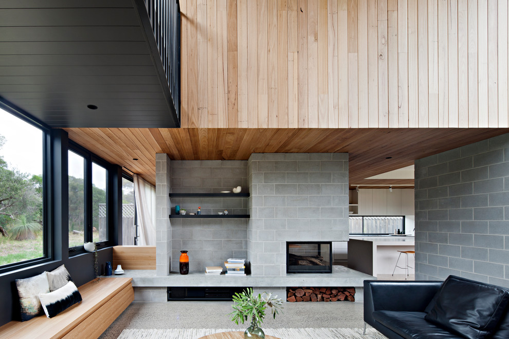 Offenes Modernes Wohnzimmer mit grauer Wandfarbe, Betonboden, Tunnelkamin, Kaminumrandung aus Beton und grauem Boden in Sonstige