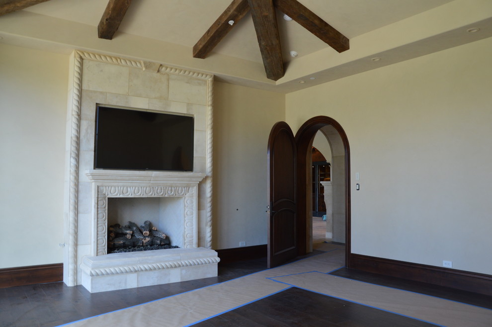 Photo of a medium sized mediterranean formal enclosed living room in San Francisco with beige walls, dark hardwood flooring, a standard fireplace, a plastered fireplace surround and a wall mounted tv.