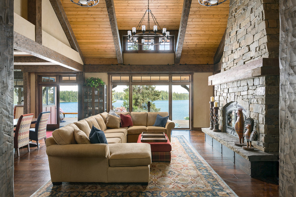 Example of a mid-sized mountain style open concept medium tone wood floor and brown floor living room design in Jackson with beige walls, a wood stove and a stone fireplace