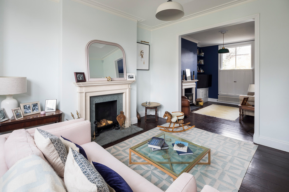 Cette image montre un grand salon traditionnel ouvert avec une salle de réception, un mur bleu, parquet foncé, un poêle à bois, un manteau de cheminée en plâtre, un téléviseur fixé au mur et un sol marron.