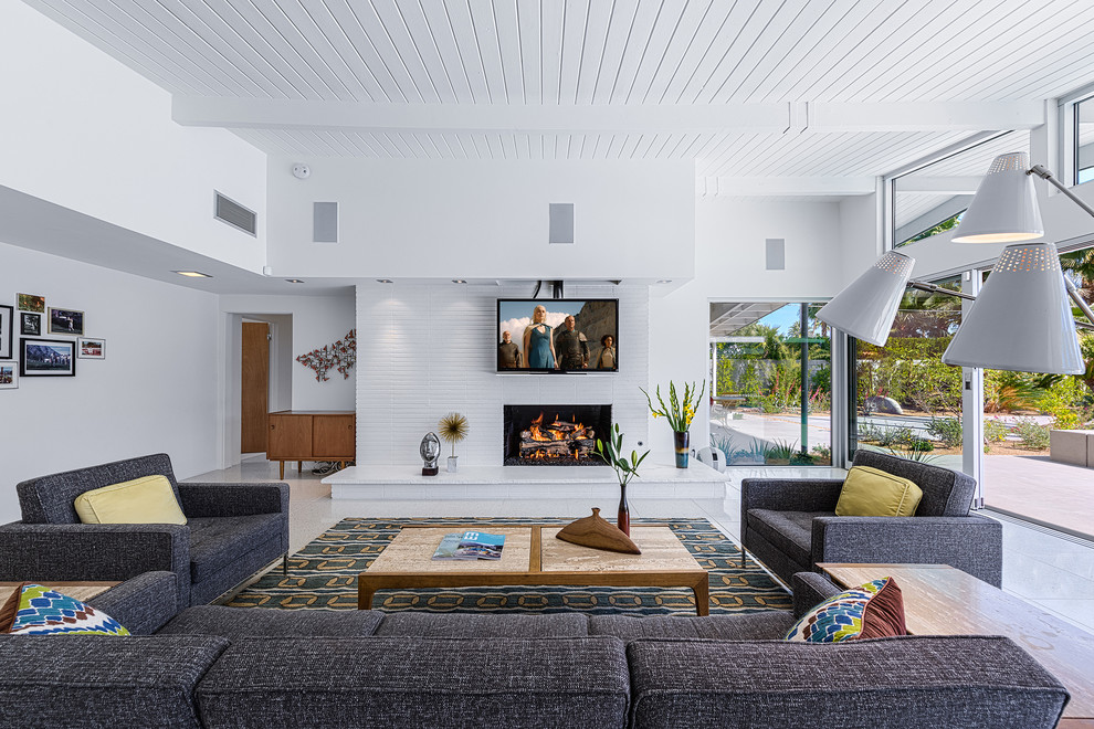 Esempio di un soggiorno moderno aperto con pareti bianche, camino classico, cornice del camino in mattoni e TV nascosta