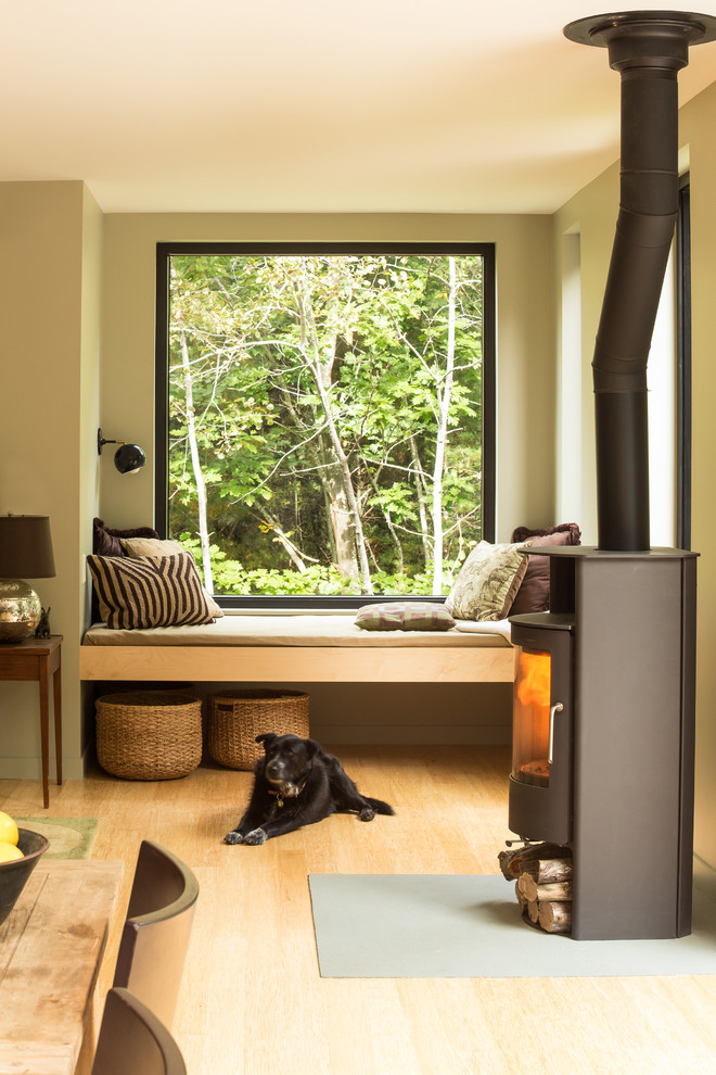 Foto de salón abierto rústico pequeño con paredes verdes, suelo de madera clara, estufa de leña y marco de chimenea de metal