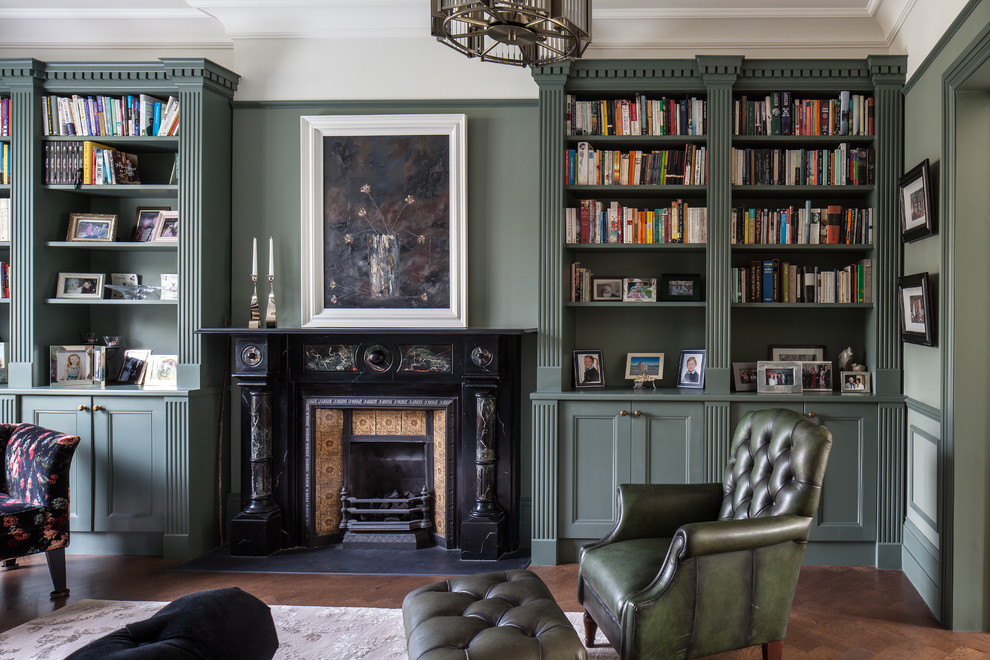 Mittelgroßes, Abgetrenntes Klassisches Wohnzimmer mit grüner Wandfarbe, dunklem Holzboden, Kamin, Kaminumrandung aus Metall und braunem Boden in London