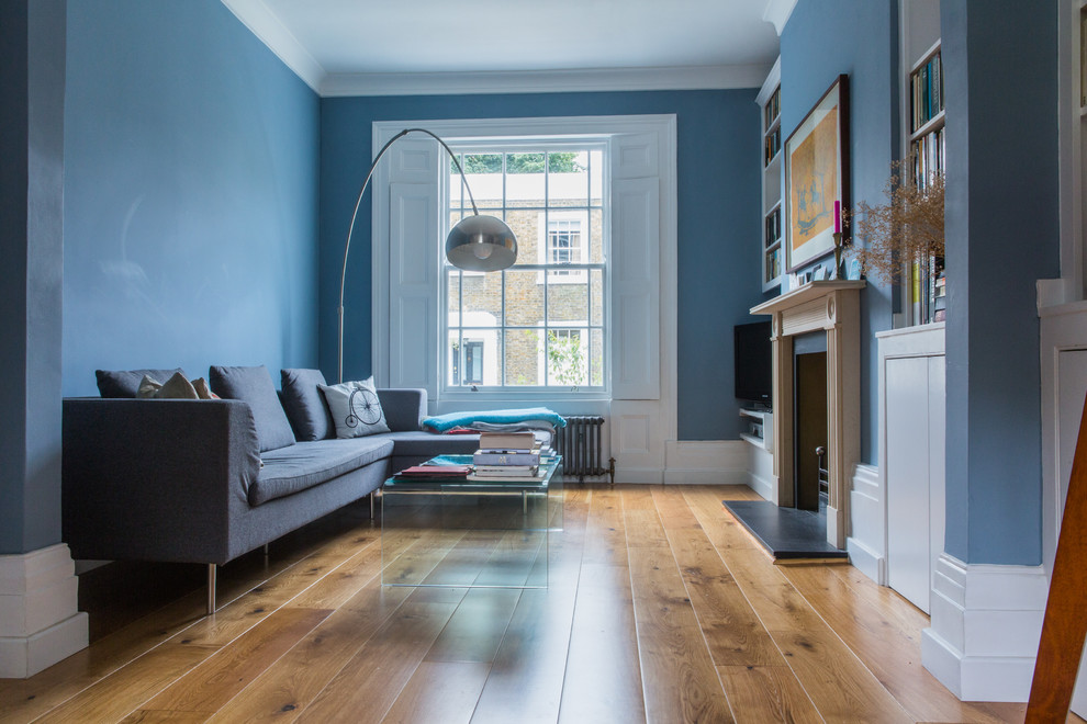 Exemple d'un salon tendance de taille moyenne et ouvert avec une salle de réception, un mur bleu, un sol en bois brun, une cheminée standard, un manteau de cheminée en pierre et un téléviseur indépendant.