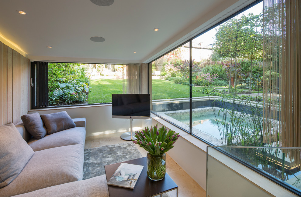 Example of a trendy living room design in London with beige walls and a tv stand