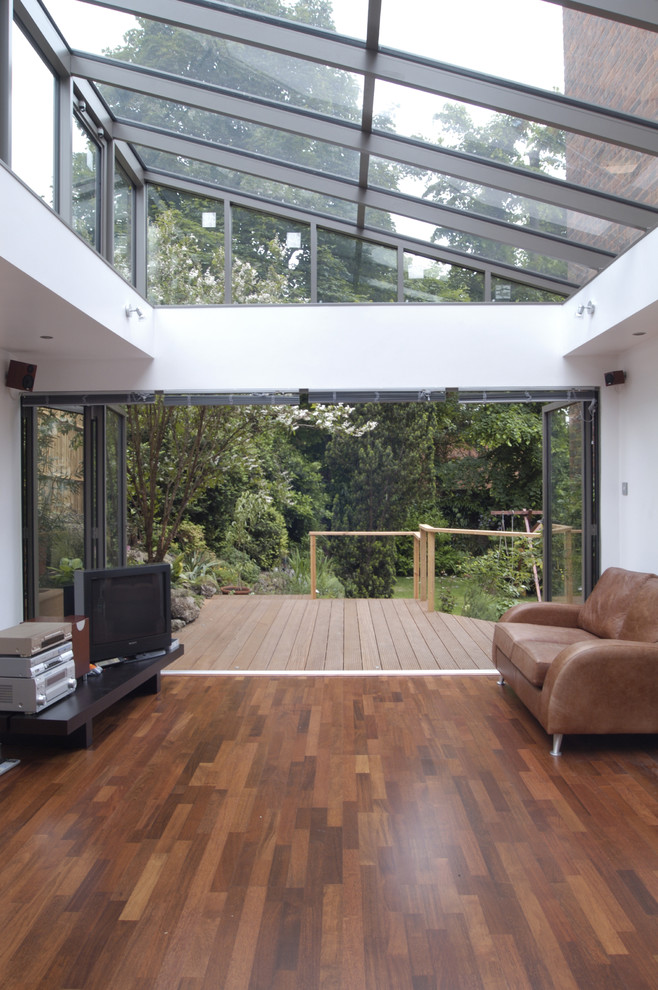 Imagen de salón cerrado contemporáneo grande con paredes grises, suelo de madera en tonos medios y estufa de leña