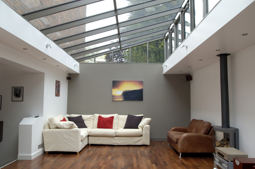 Idéer för att renovera ett stort funkis separat vardagsrum, med grå väggar, mellanmörkt trägolv och en öppen vedspis