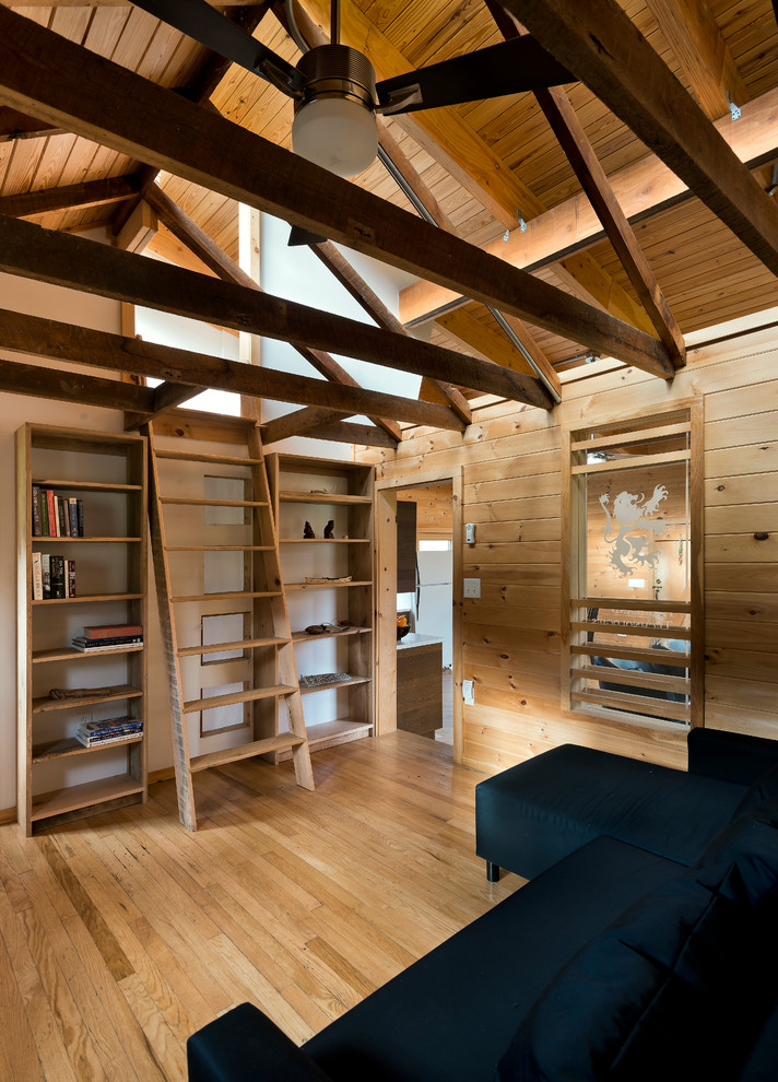 Ejemplo de biblioteca en casa tipo loft minimalista pequeña sin televisor y chimenea con paredes blancas, suelo de madera clara y suelo marrón