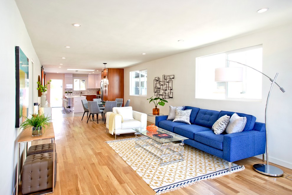 Источник вдохновения для домашнего уюта: открытая гостиная комната в современном стиле с белыми стенами, паркетным полом среднего тона и синим диваном