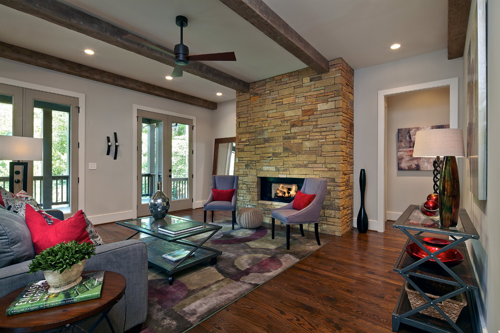 Imagen de salón abierto tradicional de tamaño medio sin televisor con paredes grises, suelo de madera oscura, todas las chimeneas y marco de chimenea de piedra