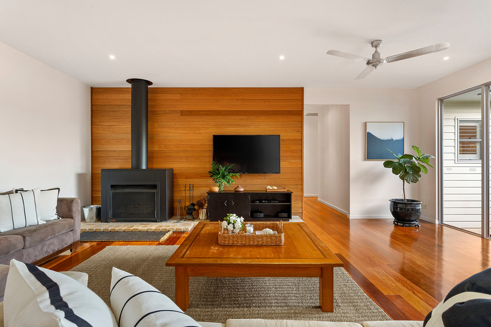 Exemple d'un salon tendance ouvert avec une salle de réception, un mur blanc, un sol en bois brun, une cheminée standard, un manteau de cheminée en métal, un téléviseur fixé au mur et un sol marron.