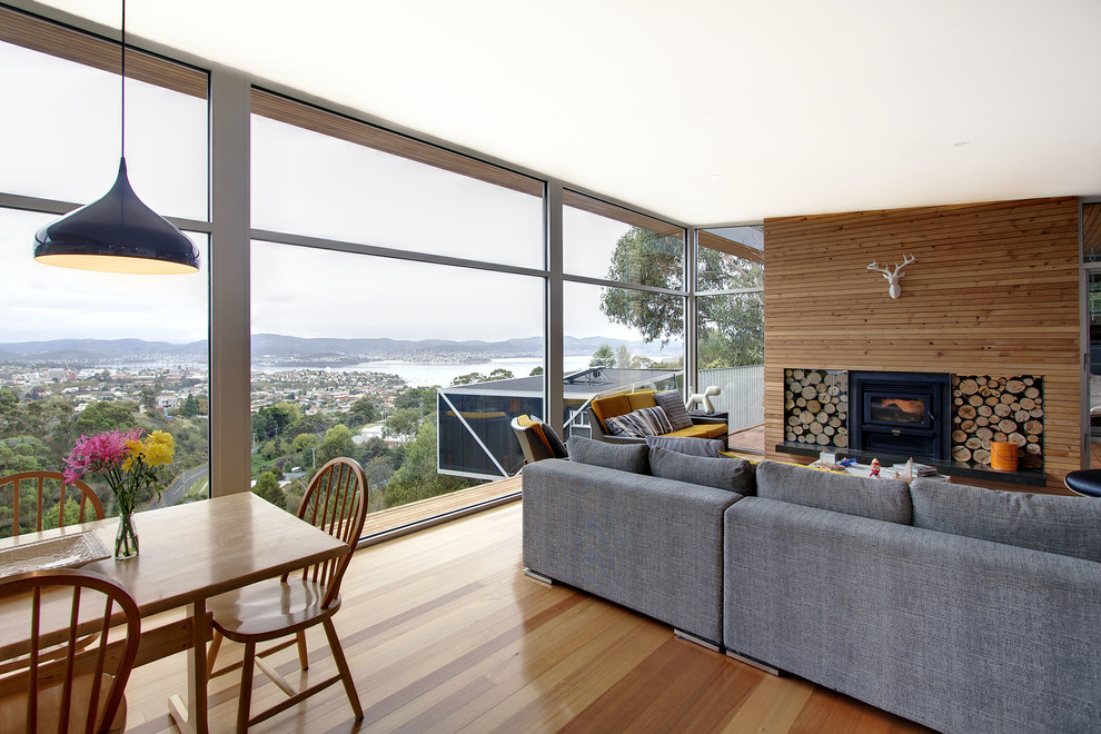 Large contemporary open plan living room in Hobart with a reading nook, beige walls, light hardwood flooring, a standard fireplace, a wooden fireplace surround and a built-in media unit.