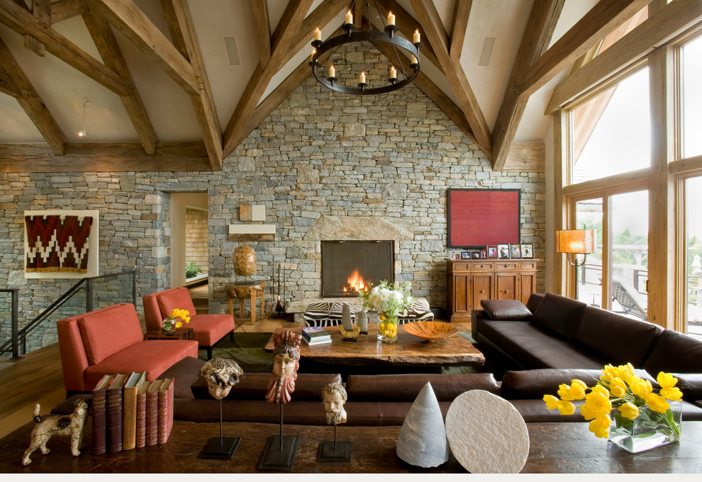 Exemple d'un salon mansardé ou avec mezzanine montagne avec une salle de réception, un sol en bois brun, une cheminée standard, un manteau de cheminée en pierre et aucun téléviseur.
