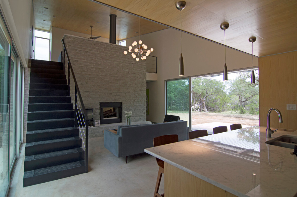 Modern inredning av ett loftrum, med betonggolv och en dubbelsidig öppen spis