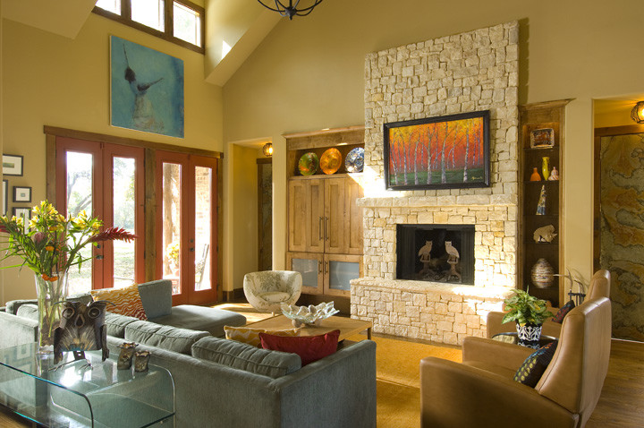 Imagen de salón abierto ecléctico con suelo de madera clara, marco de chimenea de piedra y televisor retractable