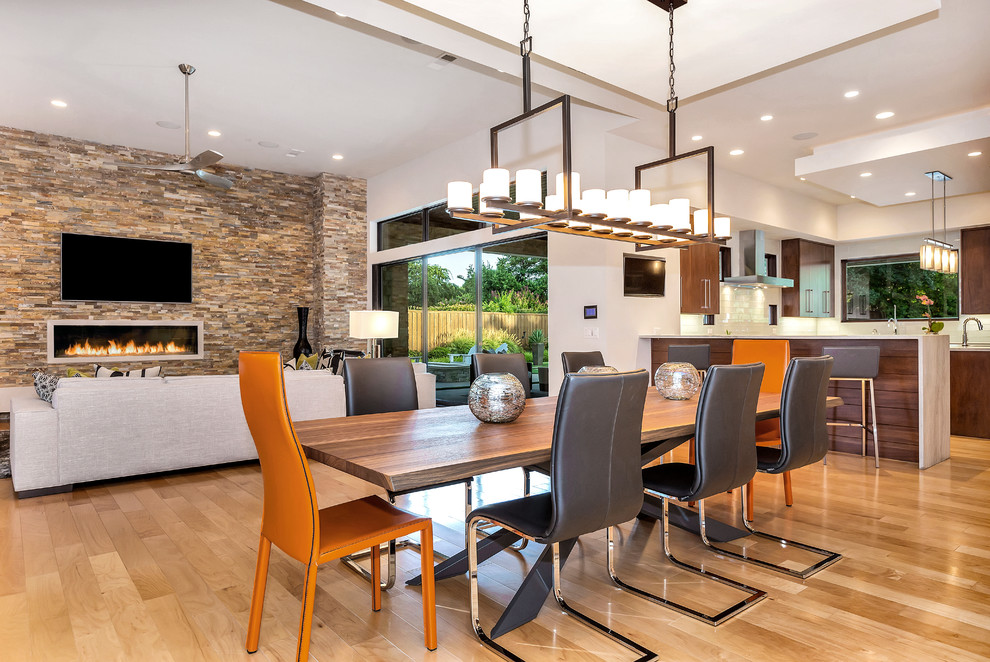 Modernes Esszimmer mit bunten Wänden, hellem Holzboden, Kaminumrandung aus Stein und braunem Boden in Dallas