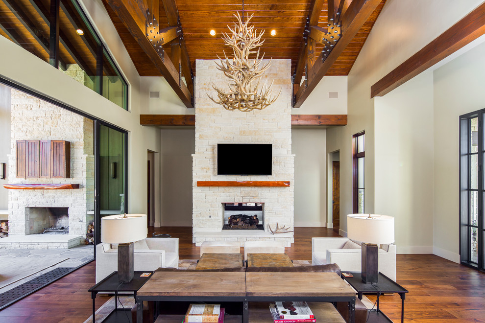 Imagen de salón para visitas abierto de estilo de casa de campo con paredes beige, suelo de madera en tonos medios, chimenea de doble cara y televisor colgado en la pared