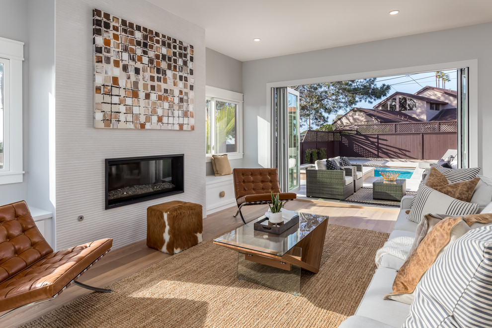 Imagen de salón para visitas abierto campestre sin televisor con paredes grises, suelo de madera clara, chimenea lineal y suelo marrón