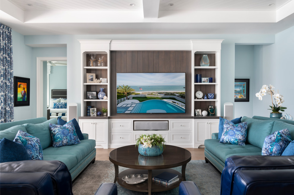 他の地域にある高級な広いビーチスタイルのおしゃれなLDK (青い壁、無垢フローリング、埋込式メディアウォール、ベージュの床、格子天井) の写真