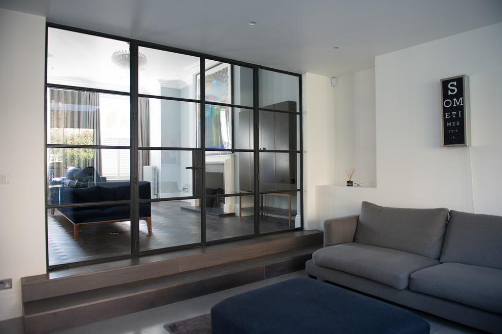 Modelo de salón abierto contemporáneo extra grande con paredes blancas, suelo de cemento, televisor colgado en la pared y suelo gris