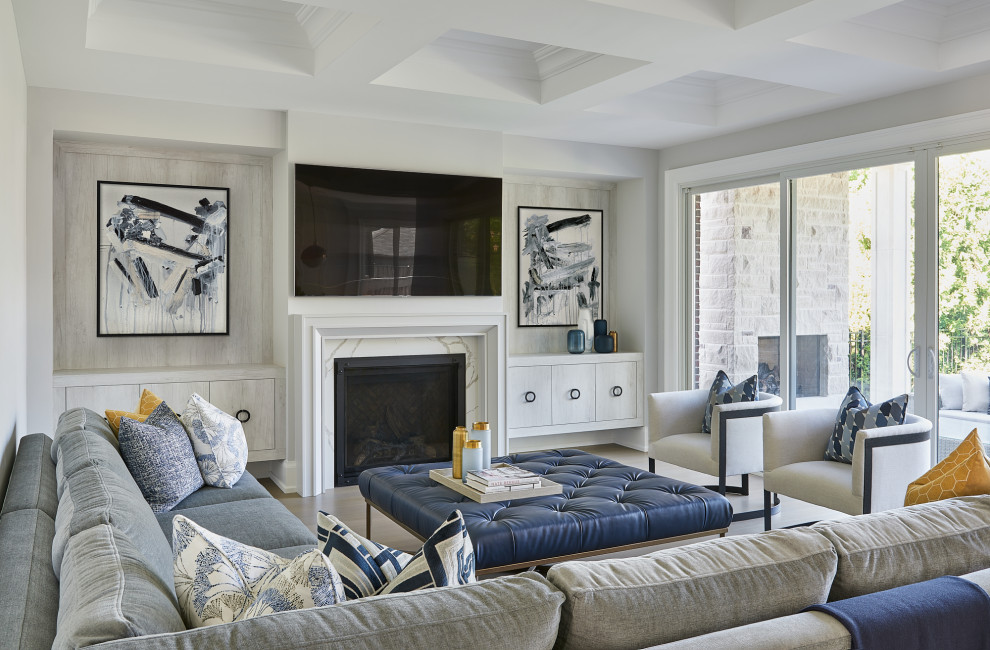 На фото: гостиная комната в стиле неоклассика (современная классика) с серыми стенами, паркетным полом среднего тона, стандартным камином, телевизором на стене и коричневым полом