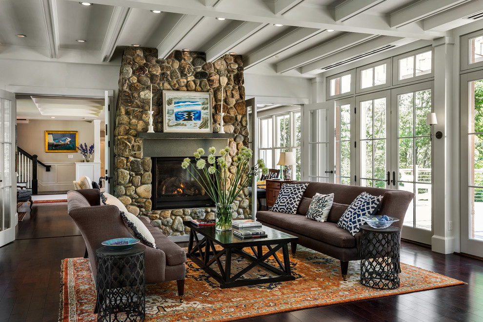 Пример оригинального дизайна: гостиная комната в морском стиле с темным паркетным полом, стандартным камином, фасадом камина из камня и коричневым диваном