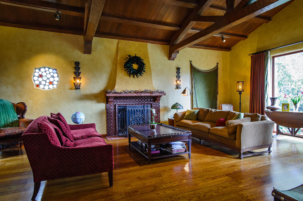Idée de décoration pour un salon tradition avec un mur jaune et une cheminée standard.