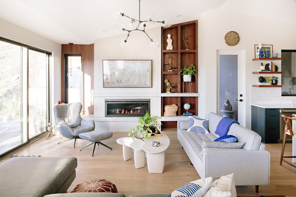 Example of a trendy formal and open concept medium tone wood floor and brown floor living room design in Vancouver with white walls, a ribbon fireplace and no tv