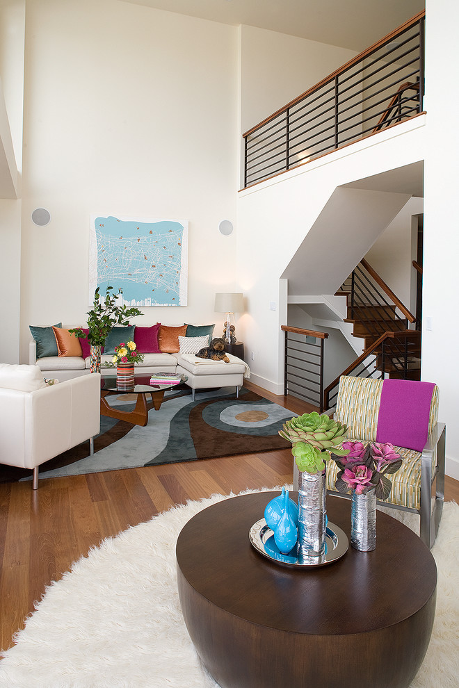 Modelo de salón para visitas abierto moderno grande con paredes blancas y suelo de madera en tonos medios