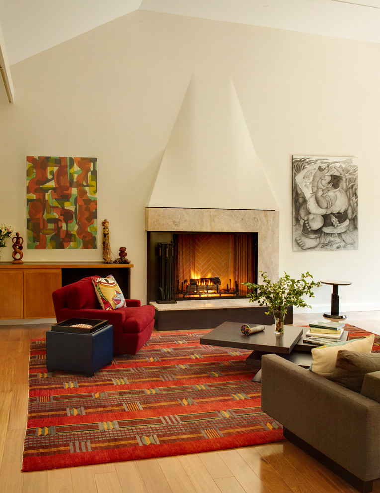 Réalisation d'un grand salon design ouvert avec un manteau de cheminée en pierre, un mur beige, une cheminée standard, un sol en bois brun, un téléviseur fixé au mur et un sol marron.