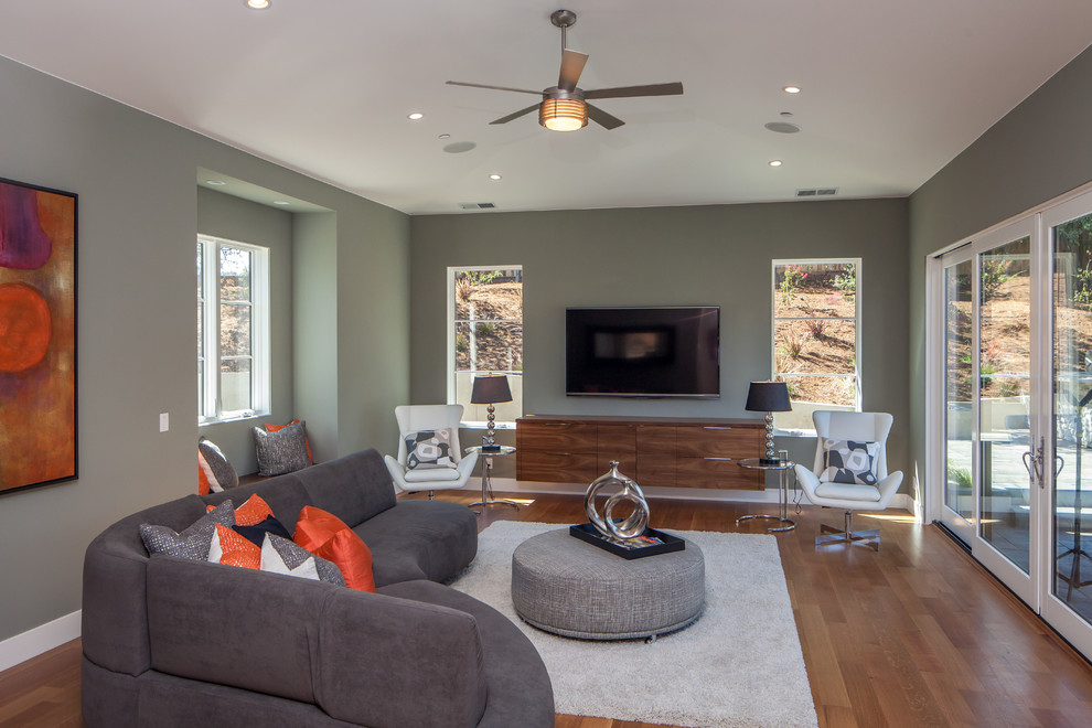 Immagine di un soggiorno design chiuso con pareti verdi, pavimento in legno massello medio e TV a parete