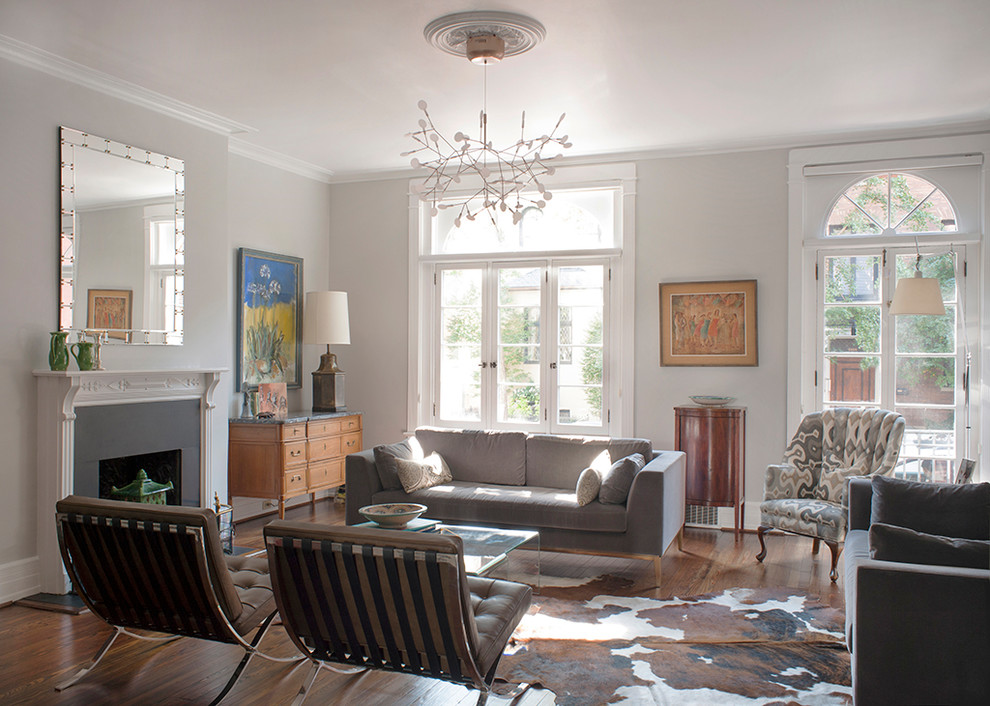 Immagine di un soggiorno classico con pareti grigie, pavimento in legno massello medio, camino classico e pavimento marrone