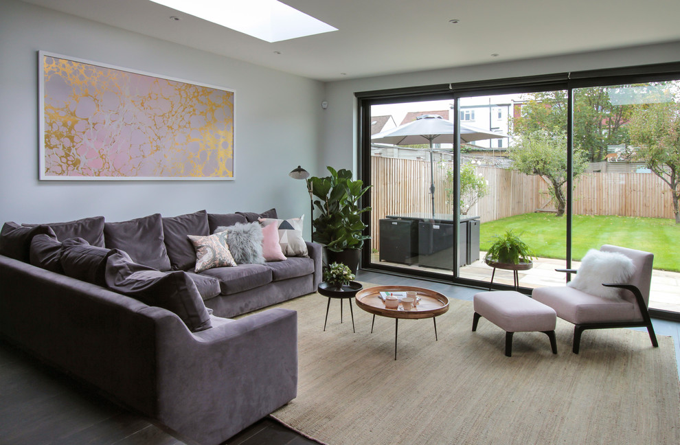 Large trendy open concept dark wood floor and black floor living room photo in London with no fireplace, a bar and gray walls