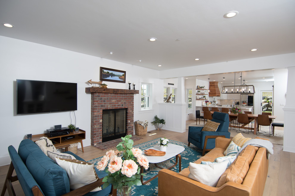 Medium sized rural open plan living room in Portland with white walls, medium hardwood flooring, a standard fireplace, a brick fireplace surround and a wall mounted tv.