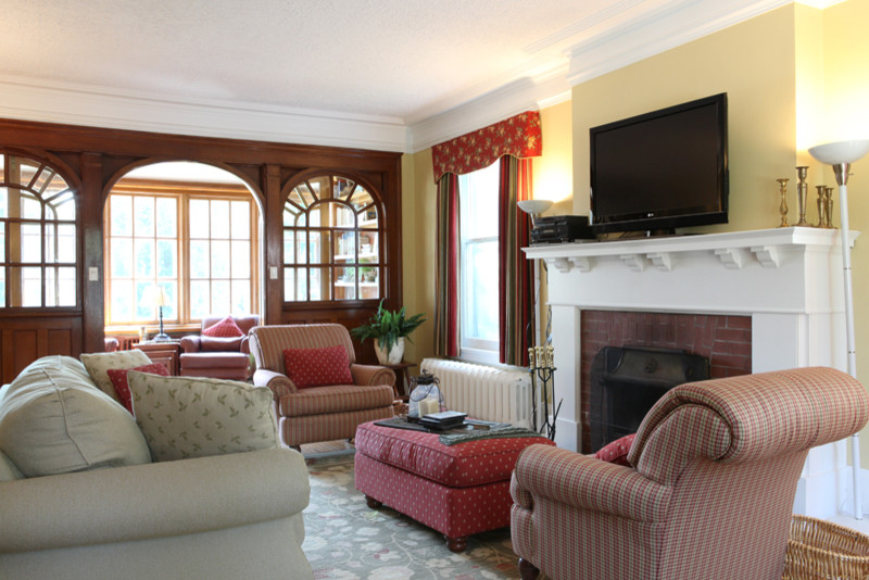 Ejemplo de salón para visitas cerrado clásico de tamaño medio con paredes amarillas, suelo de madera en tonos medios, todas las chimeneas, marco de chimenea de madera y televisor colgado en la pared