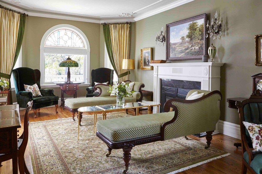 Example of a large ornate formal and enclosed medium tone wood floor and brown floor living room design in Toronto with green walls, a standard fireplace and no tv