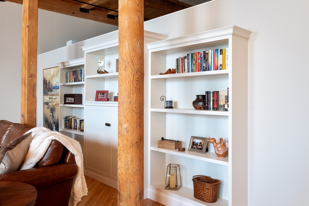 Imagen de biblioteca en casa abierta industrial extra grande con suelo de madera clara y vigas vistas