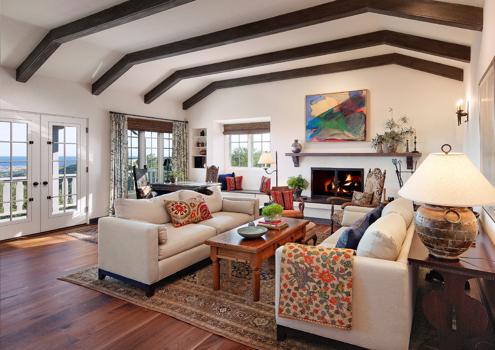 Mittelgroßes, Repräsentatives, Fernseherloses, Offenes Mediterranes Wohnzimmer mit weißer Wandfarbe, dunklem Holzboden, Kamin und verputzter Kaminumrandung in Santa Barbara